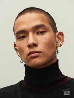 a young man with piercings on his ears looks at the camera while wearing a black turtle neck sweater