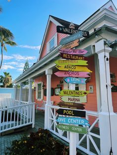 a pink house with lots of signs on the front and side of it that are pointing in different directions