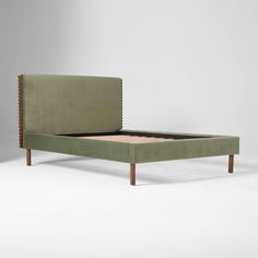 a green bed frame with wooden legs and an upholstered headboard