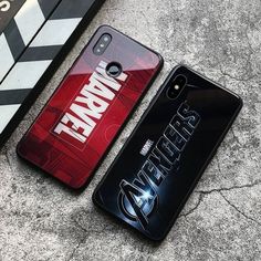 two cell phones sitting next to each other on top of a cement floor with the words avengers printed on them