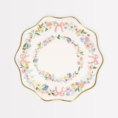 a white plate with floral designs and gold trimmings on the rim, decorated with scissors