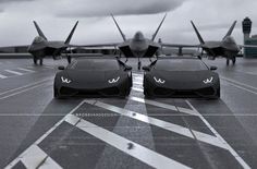 two cars on an airport runway with a plane in the background