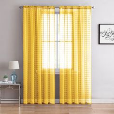 a living room with yellow curtains on the windowsill and a white table in front of it