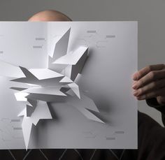 a man holding up a piece of paper with an abstract design on it