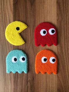 four different colored bath mitts with eyes and noses on wood background, one is shaped like a pacifier