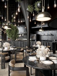 an image of a restaurant setting with black tables and chairs in the center, surrounded by hanging lights