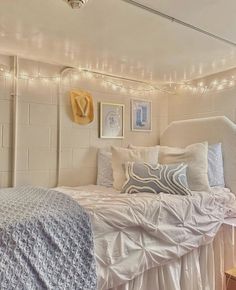 a white bed sitting next to a window covered in lights