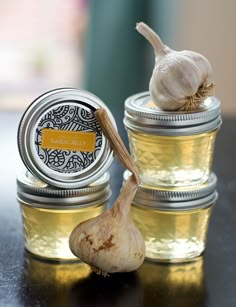 three jars filled with garlic sitting on top of a table next to an onion peel