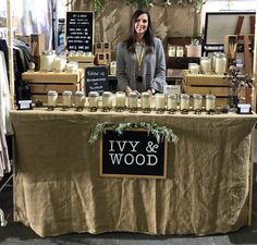 a woman standing behind a table that has candles on it and signs above the table