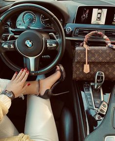 a woman sitting in the driver's seat of a car with her hand on the steering wheel