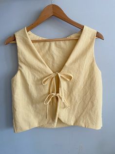 a cropped top hanging on a wooden hanger next to a blue wall with an object in it