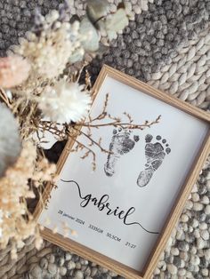 a baby's hand and foot prints are displayed in a frame next to dried flowers