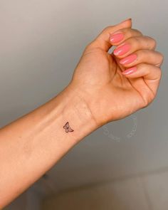 a woman's arm with a small butterfly tattoo on the left side of her wrist