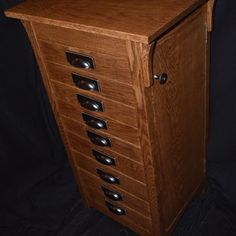 a wooden cabinet with many drawers and knobs on the front, sitting against a black background