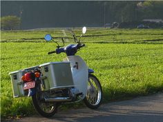 a scooter parked on the side of a road in front of a grassy field