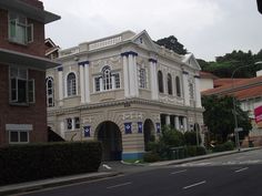 an old building with blue and white trim on the corner of a street in front of some buildings