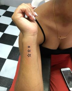 a woman's arm with three stars on it and a cell phone next to her