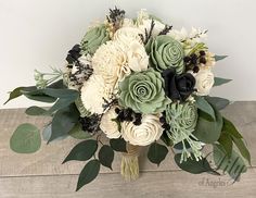 a bouquet of white and green flowers sitting on top of a wooden table