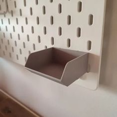 a white wall mounted shelf with holes in the middle and a paper holder attached to it