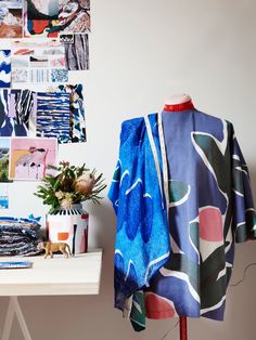 a dress on a mannequin in front of a wall with pictures and plants