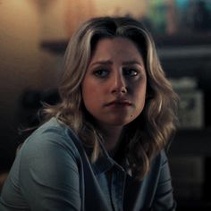 a woman sitting in front of a table looking at the camera with an intense look on her face