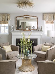 a living room with couches, chairs and a table in front of a fireplace