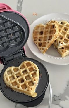 heart shaped waffles are on a plate next to a pink and black waffle maker