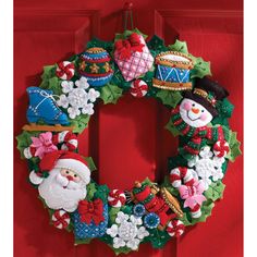 a christmas wreath hanging on a red door with santa clause and snowmen around it