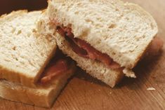 a sandwich cut in half sitting on top of a wooden cutting board