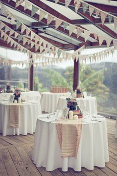 an outdoor venue with tables and chairs covered in white linens, decorated with bunting