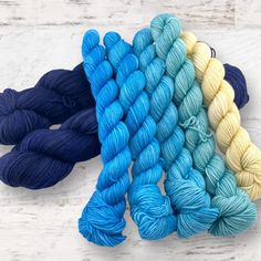 four skeins of yarn in different colors on a white wooden surface with text overlay