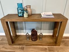 a wooden table with two vases on top of it and an animal figurine under the shelf