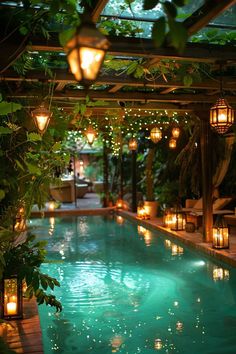 an indoor swimming pool surrounded by lanterns and greenery with lights hanging from the ceiling