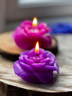 three candles are sitting on top of a piece of wood with one candle lit in the middle