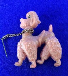 a keychain shaped like a poodle on a blue surface with a chain