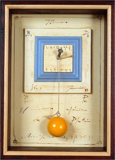 an orange hanging from a blue and white clock with writing on the wall behind it