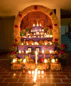 candles are lit in front of a decorated altar with skulls and flowers on it, surrounded by pumpkins