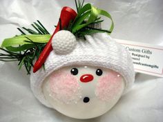 a white ornament with a red nose and green leaves on it's head