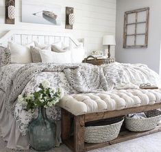 a bed with white sheets and pillows in a bedroom next to a table with baskets on it