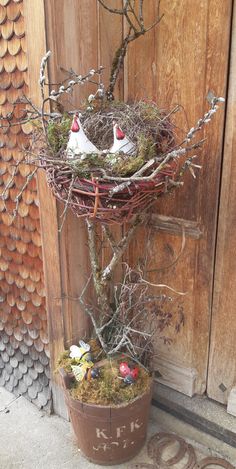 two birds sitting in a nest on top of a planter next to a wooden door