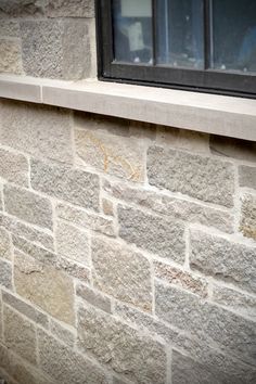 a cat sitting on the ledge of a window sill next to a brick wall