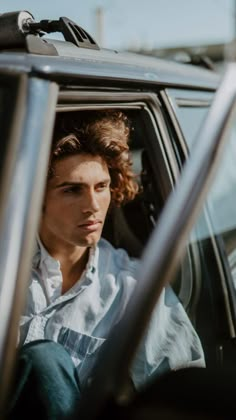 a man sitting in the driver's seat of a car with his head out the window