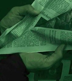 two hands are holding newspapers and reading the same paper in front of each other on a dark green background