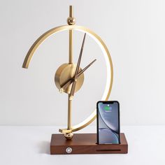 an iphone is sitting on a stand next to a clock and cell phone in front of it