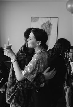 black and white photograph of two people hugging each other while holding coffee cups in their hands