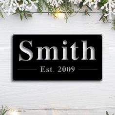 a black and white sign that says smith est 2009 with snowflakes in the background