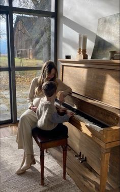 a woman sitting at a piano with a child