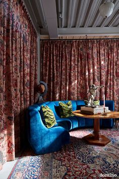 a living room filled with blue couches next to a window covered in red curtains