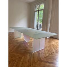 an empty room with wooden floors and a table in the middle that is made out of plexed glass