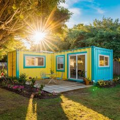 a blue and yellow container house sitting in the grass